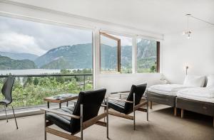 Un dormitorio con una cama y sillas y una gran ventana. en Energihotellet, en Nesflaten 15 fotos más