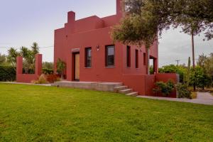 een rood huis met een gazon ervoor bij Red Castle in Souda