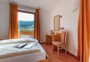 a bedroom with a bed and a desk and a mirror at Chalet Loredana in Livigno