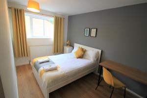 ein Schlafzimmer mit Bett, Schreibtisch und Fenster in der Unterkunft Hamilton House -3 bed Close to Town, Drive Parking, 2 toilets in Newcastle upon Tyne