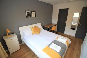 ein Schlafzimmer mit einem Bett mit weißen Laken und orangefarbenen Kissen in der Unterkunft Hamilton House -3 bed Close to Town, Drive Parking, 2 toilets in Newcastle upon Tyne