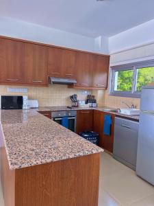 a kitchen with wooden cabinets and a granite counter top at 3 Bedroom Coral Bay Beach Seaview Villa I Private Pool in Peyia