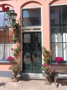 um edifício cor-de-rosa com uma porta verde e flores em De Zevenster "gevestigd aan de winkelstraat" em Kampen