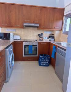 a kitchen with wooden cabinets and a washer and dryer at 3 Bedroom Coral Bay Beach Seaview Villa I Private Pool in Peyia