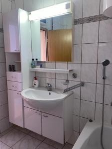 uma casa de banho branca com um lavatório e um espelho em Obiteljska kuća u centru Posušja em Posusje