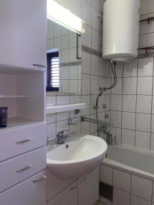a white bathroom with a sink and a bath tub at Obiteljska kuća u centru Posušja in Posušje