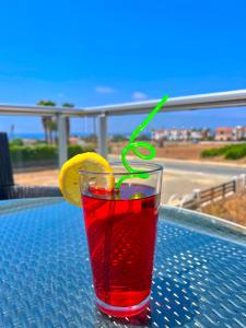 a drink with a green straw sitting on a table at 3 Bedroom Coral Bay Beach Seaview Villa I Private Pool in Peyia