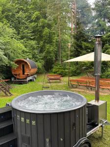 a hot tub in a yard with a tent and benches at Weekend house w lesie, na Kaszubach in Rybaki