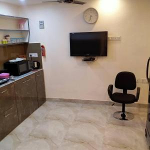 a room with a chair and a tv on a wall at Rose Premium Studio Apartment by Hotel Airways in Kolkata