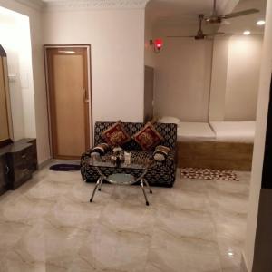 a living room with a couch and a table at Rose Premium Studio Apartment by Hotel Airways in Kolkata