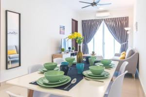 uma sala de jantar com uma mesa com pratos verdes em Simfoni Tower 3R2B 8pax @C180@Chr Trader Square em Seri Kembangan