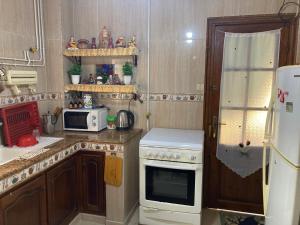 La cuisine est équipée d'une cuisinière blanche et d'un réfrigérateur. dans l'établissement Location appartement Oran Akid lotfi, à Oran