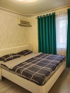 1 dormitorio con 1 cama grande y cortinas verdes en Амид 3 en Khujand
