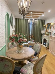 a dining room with a table and chairs with a vase of flowers at Princess Vinhomes Smart City Apartment in Hanoi