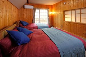 Dos camas en una habitación con paneles de madera. en The LODGE ABASHIRI, en Abashiri 108 fotos más