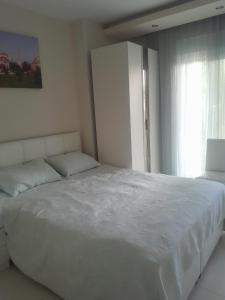 a white bed in a bedroom with a window at Konyaaltı Denize Yakın Kiralık Daire in Antalya