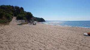 a beach with people sitting on the sand and the water at Apartament Vallarta in Kavarna
