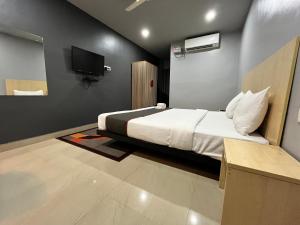 um quarto com uma cama e uma televisão na parede em RJB Grand em Guwahati