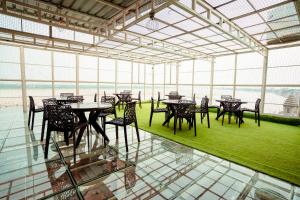 - une salle à manger avec des tables et des chaises dans une pièce dotée de fenêtres dans l'établissement HOTEL JSR GANGA, à Varanasi