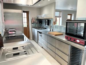 a large kitchen with stainless steel counters and appliances at 't Hooiland in Lo-Reninge