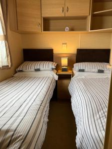two twin beds in a small room with a lamp at Countryside 3-bedroom Static Caravan in Llanerchymedd
