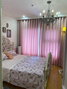 a bedroom with a bed with pink curtains and a chandelier at Princess Vinhomes Smart City Apartment in Hanoi