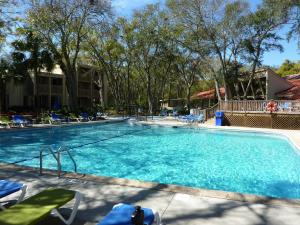 una piscina en un complejo con sillas y árboles en VILLA 176 - Villa Delmar condo en Jekyll Island