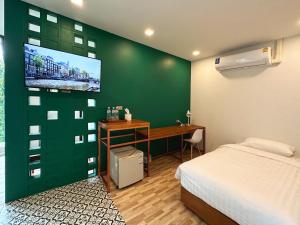 a bedroom with a green wall with a bed and a desk at Plernpetch Hotel in Surat Thani