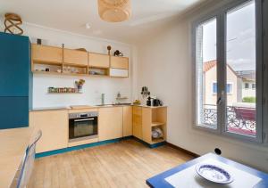 a kitchen with wooden cabinets and a large window at Le NID du STADE de FRANCE in Saint-Denis