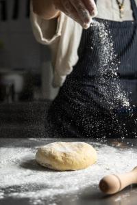 a person sprinkling flour on top of a dough at Bohemia Luxury Living in Hanioti