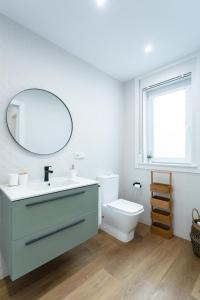 a bathroom with a sink and a toilet and a mirror at Zalaeta Playa Apartments in A Coruña