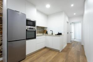 a kitchen with white cabinets and a stainless steel refrigerator at Zalaeta Playa Apartments in A Coruña