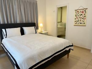 een slaapkamer met een groot bed met witte lakens bij Roza Apartment in Tel Aviv