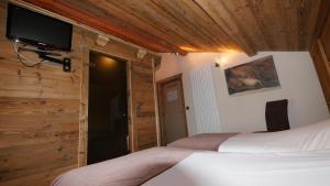 Hotel Bel'alpe في مورزين: غرفة نوم مع سرير وتلفزيون على الحائط