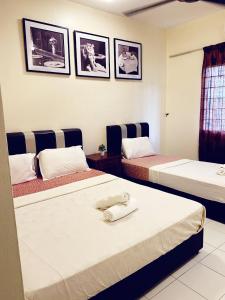 2 Betten in einem Zimmer mit Bildern an der Wand in der Unterkunft PD Lagoon Resort in Port Dickson