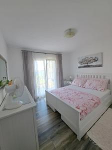a white bedroom with a bed and a mirror at Apartman Prošperino in Vis