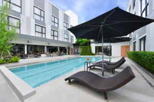 a pool with chairs and an umbrella next to a building at Gate43 Garden Villa in Bangkok