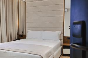 a bedroom with a white bed and a television at Duka's Hotel in Ksamil