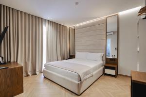 a bedroom with a white bed and a large window at Duka's Hotel in Ksamil