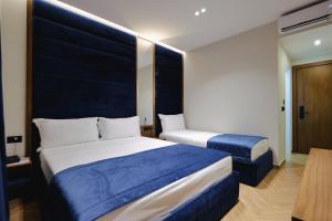 a bedroom with two beds with blue and white sheets at Duka's Hotel in Ksamil