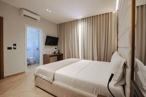 a bedroom with a white bed and a television at Duka's Hotel in Ksamil