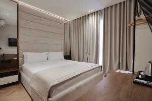a bedroom with a large white bed and a window at Duka's Hotel in Ksamil