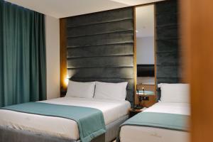 two beds in a hotel room with green curtains at Duka's Hotel in Ksamil