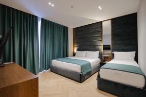 two beds in a hotel room with green curtains at Duka's Hotel in Ksamil