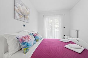 a white bed with a pink blanket and pillows on it at Feniks Fažana apartman in Fažana