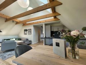 eine Küche und ein Wohnzimmer mit einem Holztisch mit Blumen in der Unterkunft Der Schuppen in Mildstedt
