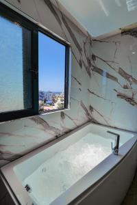 a bathroom with a bath tub with a window at Duka's Hotel in Ksamil