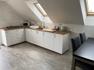 an attic kitchen with white cabinets and a sink at Apartmán Jenčice v Českém středohoří in Jenčice