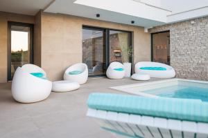 a patio with white chairs and a swimming pool at Villa Fortunal in Murter