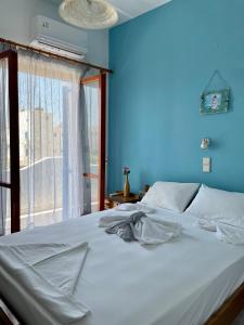 a blue bedroom with a white bed with a window at Panorama Rooms in Agia Roumeli